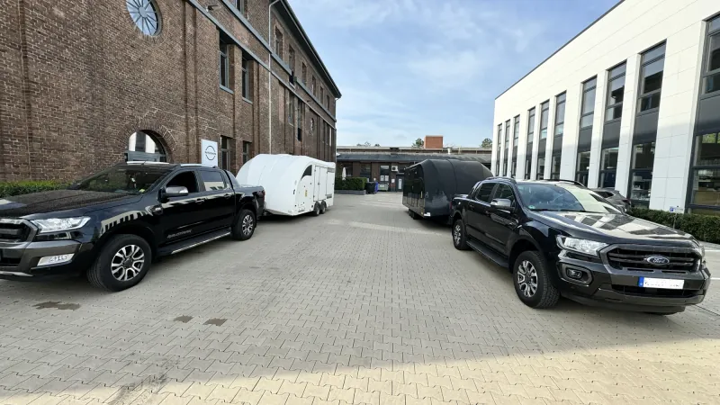 Zwei dunkle Zugfahrzeuge mit geschlossenen Transportanhängern aus dem Originalbildbestand von K.P.-Transporter